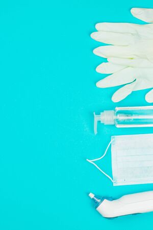 Medical mask, thermometer, white latex gloves and hand sanitizer gel on blue background. Coronavirus protection. Top view. Flat lay.の写真素材