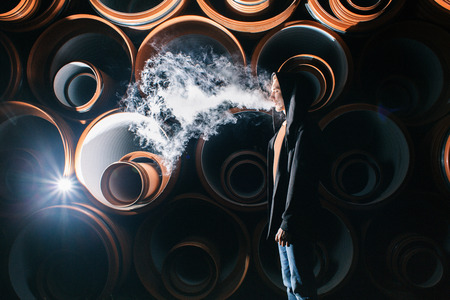 The man smokes an electronic cigarette in drama lighting