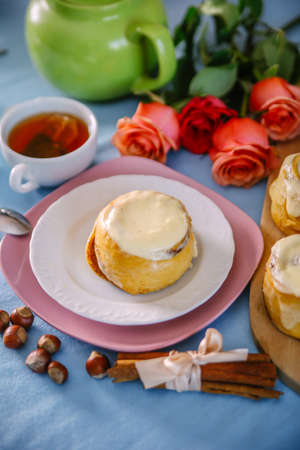bun with cinnamon and kremoi on a pink plate in a romantic setting with roses