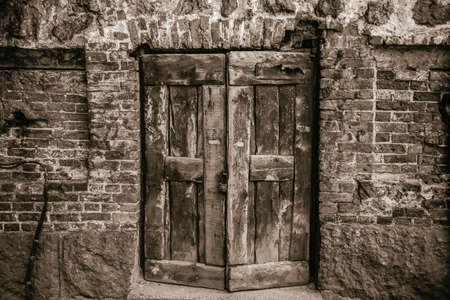 old wooden door in a brick wall with lockの写真素材