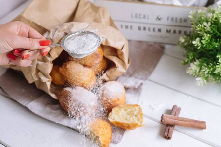 Cottage cheese donuts with cinnamon cooked at home, packed in a craft bag. Donuts sprinkled with...