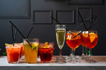 Set of cocktails and champagne in a glass on the bar table top made for party guests. Dark background of loft wall.の写真素材