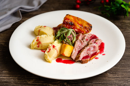 Grilled duck breast with pineapple with mashed yams and cherry sauce on a white plate. Serving by the chef as in a restaurant.の写真素材