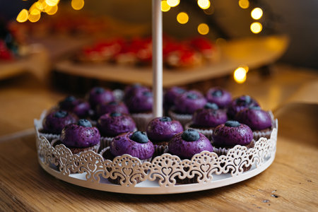 Chocolate cupcakes with purple cream and blueberries on top. In the background, a bokeh effect from the yellow lights.の写真素材