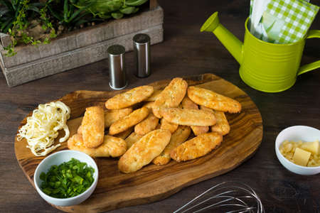 Cheesy breadsticks. Wooden board with cheesebread fingers. Food to eat with your hands. homemade baking.の写真素材