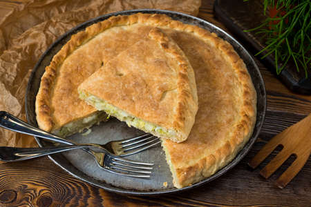Closed cabbage pie made with yeast dough on a metal baking sheet. Traditional Russian cuisine.の写真素材