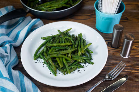 Green beans steamed, drizzled with oil and salt. White plate with a portion of cooked beans. Healthy eating and calorie control. Ideal for vegetarians.の写真素材