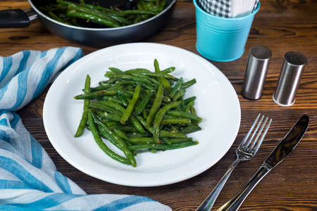 Green beans steamed, drizzled with oil and salt. White plate with a portion of cooked beans. Healthy eating and calorie control. Ideal for vegetarians.の写真素材