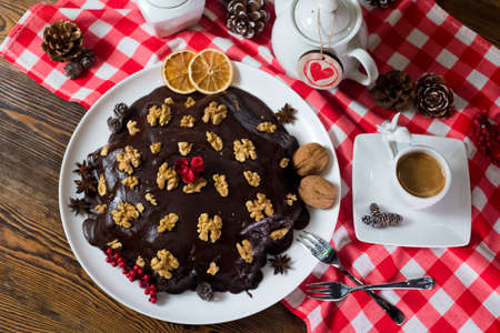 Biscuit layered cake, covered with chocolate glaze (ganache), sprinkled with walnuts. Served with tea.の写真素材