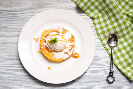 A ball of creamy vanilla ice cream on a slice of fried pineapple with caramel sauce. One serving on a white plate.の写真素材