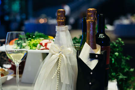 Two bottles of champagne on the wedding table in the bride and groom's suits.の写真素材