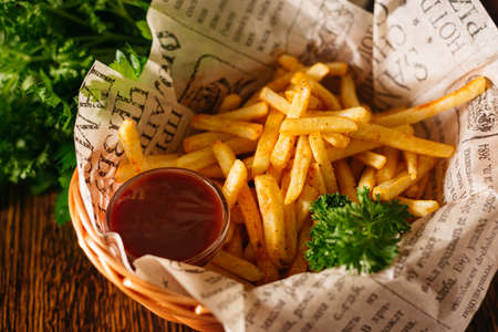 Portion of French fries and ketchup sauce. Bar food served in a basket. Crispy fries with parsley leaves.の写真素材