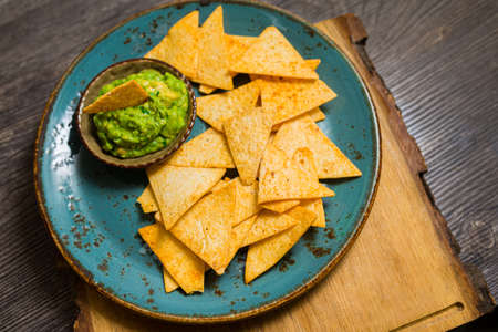 Plate of nacho chips with guacamole sauce. Handmade utensils. Mouth watering. party food.の写真素材