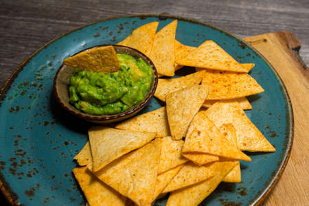 Plate of nacho chips with guacamole sauce. Handmade utensils. Mouth watering. party food.の写真素材