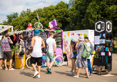young people walking through a festival of street fashion and culture. bright sunshine, hot summer,...