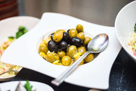 Plate with olives. Served on a plate with lemon. A buffet line with appetizers.の写真素材