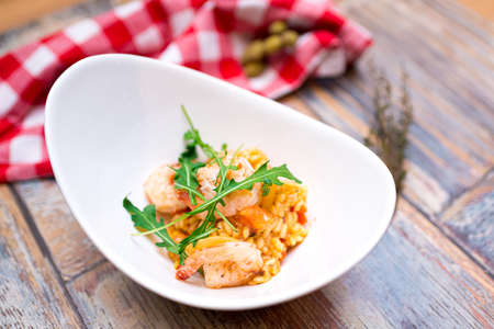 A portion of risotto with shrimp, seafood and arugula in a deep boat plateの写真素材