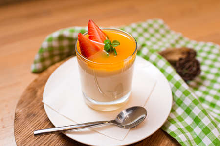 dessert in a glass parfait with strawberries and mango sauce. one portion. view above slightly.