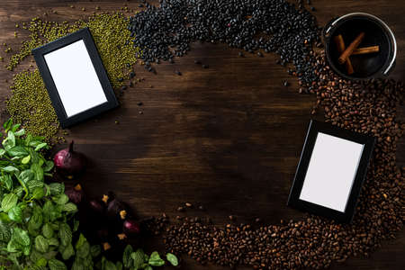 Dark wooden background with a culinary theme. The view is strictly from above. A scattering of pine nuts, black and green beans, dried red onions, two empty frames for photos or text.の写真素材