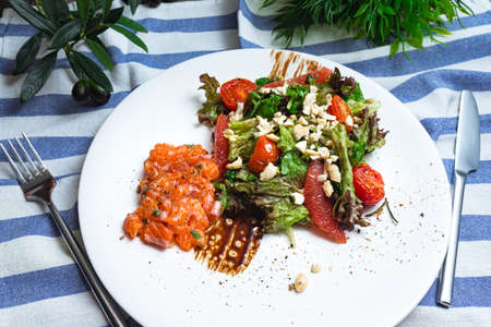 Salad with salmon, crushed cashew nuts, cherry tomatoes, balsamic sauce and grapefruit slicesの写真素材