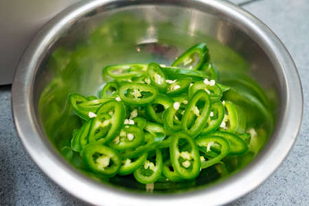 metal bowl with ring-cut green chili hot peppers, ingredients ready to cookの写真素材