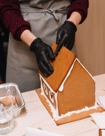 the process of making a gingerbread house, gluing the ginger roof with icing, squeezing tightの写真素材