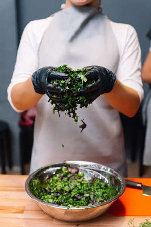 the girl is holding chopped herbs in her hands, the finely chopped herbs fall into a bowlの写真素材