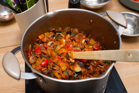 sautÃ©ed vegetables in a pot on an electric stove with a wooden spatula. top view of the kitchen table.の写真素材