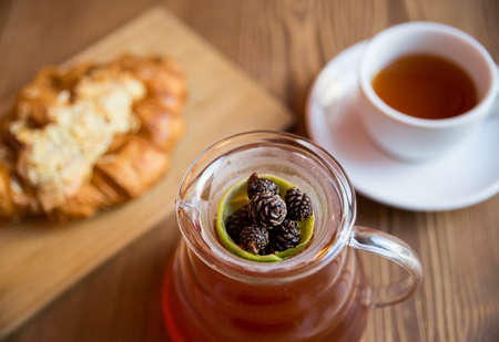 Breakfast in the cafe. juniper tea with lime served in a glass decanter, a cup of hot tea and a croissant with almonds.の写真素材