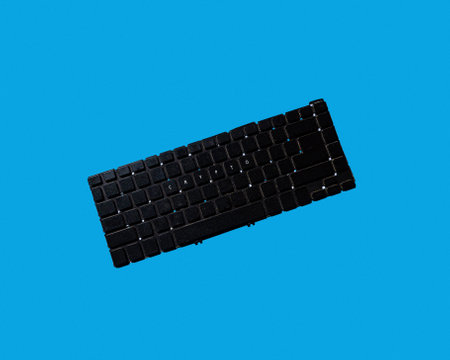 black laptop keyboard says crypto. minimalistic style. solid blue background. modern technology.