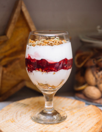 Cherry yoghurt parfait with crispy granola on top in a wine glassの写真素材