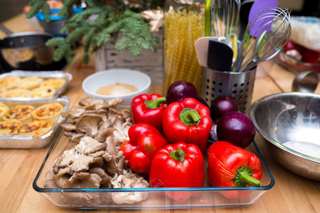 Set of raw red onions, red bell peppers, fresh oyster mushrooms in a glass dish. Kitchen table before cooking.の写真素材