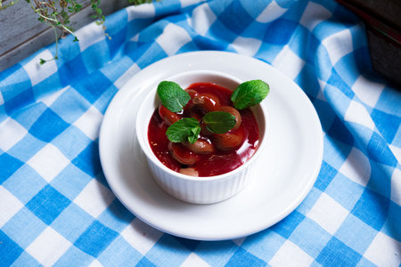 A portion of chocolate mousse with berry coulis decorated with mint leaves. Ramekin on a plate on a checkered napkin.の写真素材