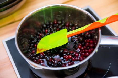cranberries are boiled in a saucepan to become jam. acrylic spatula stirs themの写真素材