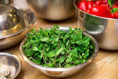 A full bowl of fresh mint leaves. Raw ingredients on the table before cooking.の写真素材
