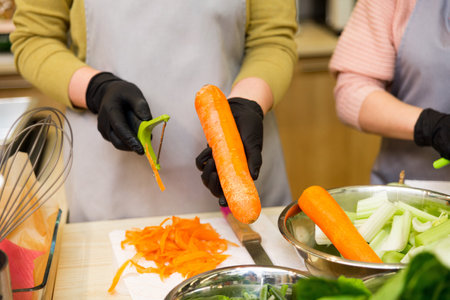 women's hands hold a vegetable peeler and peel carrots, the process of cooking, culinary classの写真素材
