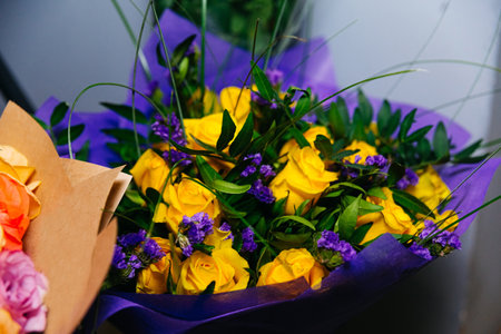 Bouquet of yellow roses and purple flowers in a purple satin wrapの写真素材
