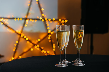 Glasses of champagne on table in room decorated with starshaped lights, closeup. Alcoholic beverages at the event.の写真素材