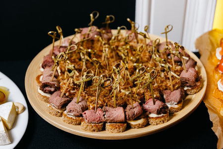 Roast beef canape on skewers. Canape with red meat and rye bread on a wooden plate. Canape tuna...