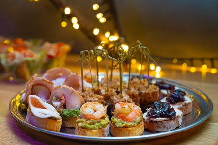 Set of bruschetta and canapes on a plate. Tapas with guacamole and prawn, tapas with caramelized onions, bruschetta with turkey fillet. Tuna canapes with tuna shavings.の写真素材