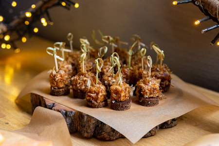 Canapes with tuna and tuna shavings on a rye bread all together with skewers on a wooden boardの写真素材