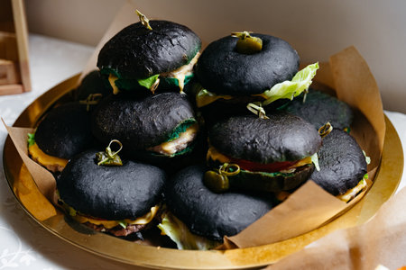 Black burgers with cheese, lettuce, tomato, cucumber and olivesの写真素材