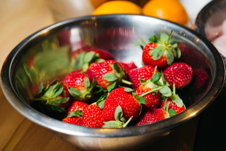 Strawberries in a metal bowl on a wooden table. Selective focus.の写真素材