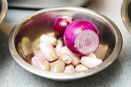 purple onion, shallot onion and garlic in a stainless steel bowl on the kitchen table