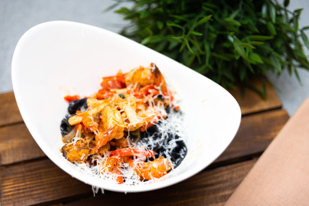Italian-style penne pasta mixed with a rich tomato sauce, black olives, and sprinkled with shredded...