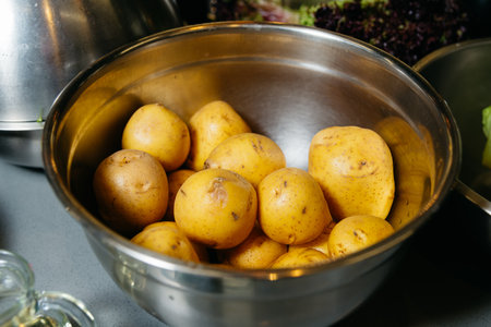 A bowl full of unpeeled raw yellow potatoes, a staple ingredient for many recipes, on a kitchen countertop.の写真素材