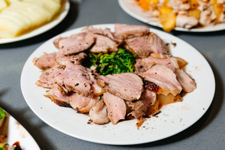 Herb-crusted roast pork sliced and plated with garnish, showing the juicy tenderness and savory flavors of the meat.の写真素材