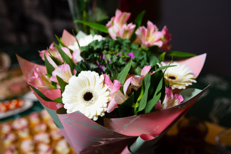 A bouquet of gerberas and assorted flowers elegantly wrapped in a decorative paper, adding a touch of beauty to any occasion.の写真素材