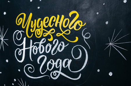 A chalkboard featuring artistic yellow and white New Year greetings written in Cyrillic script, surrounded by decorative doodles.の写真素材