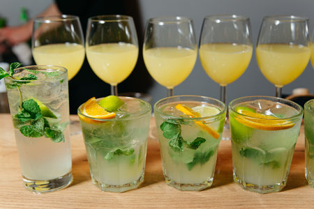 Variety of refreshing citrus cocktails including mojitos and orange drinks, served on a bar counter.